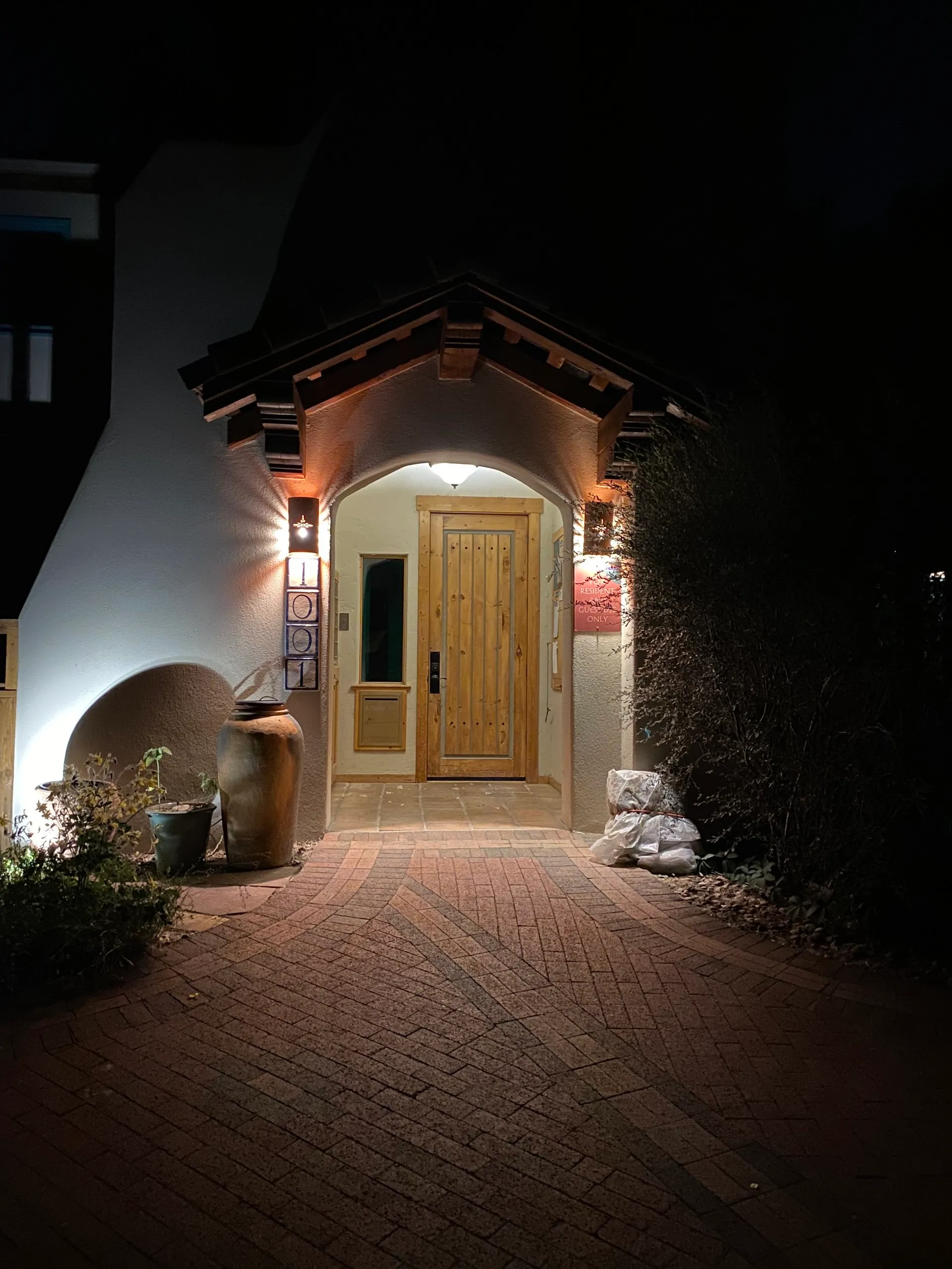 Warmly lit Common House doorway welcoming evening visitors.