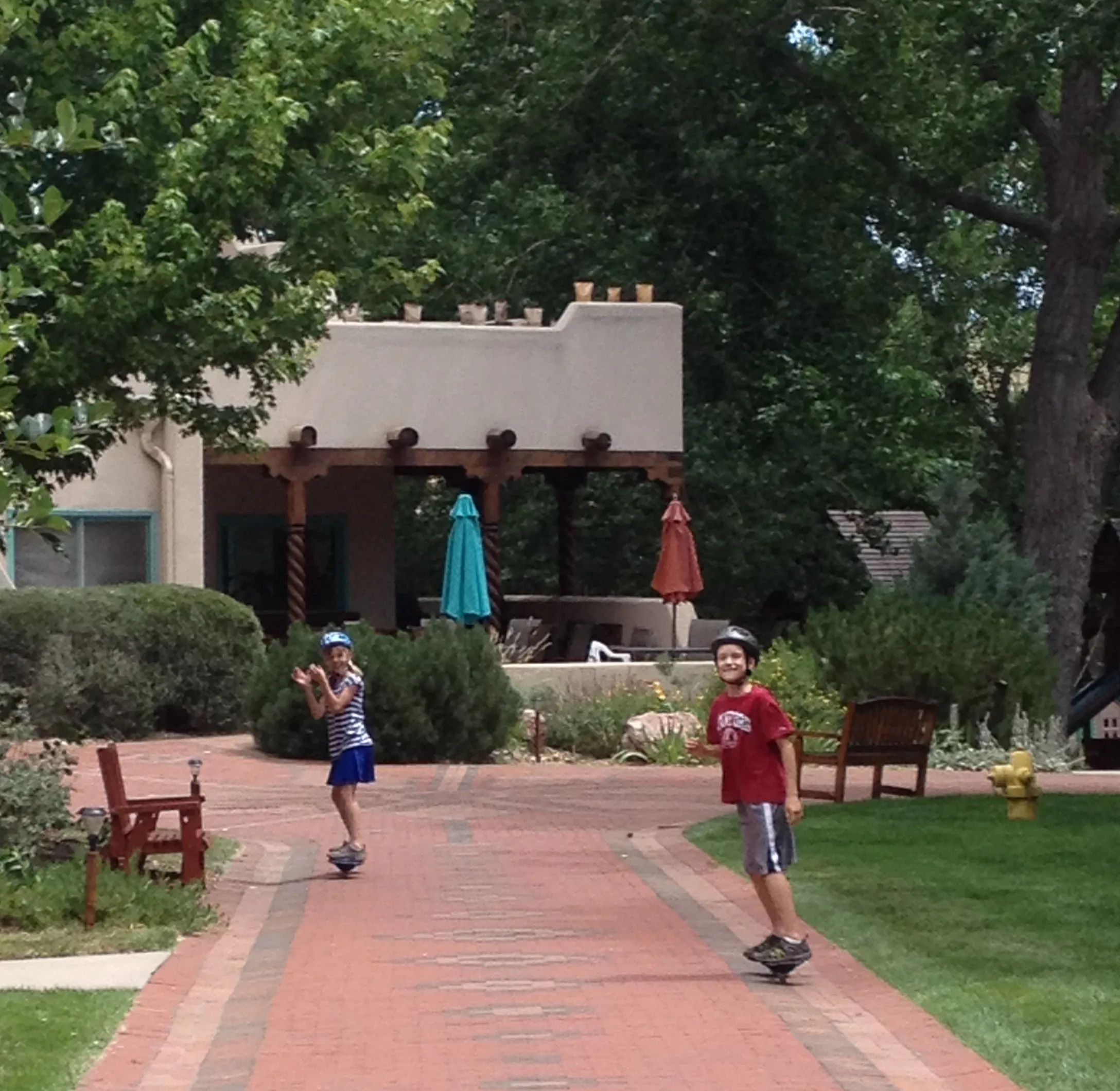 Children playing and running on brick pathway at the Common House plaza with mature landscaping
