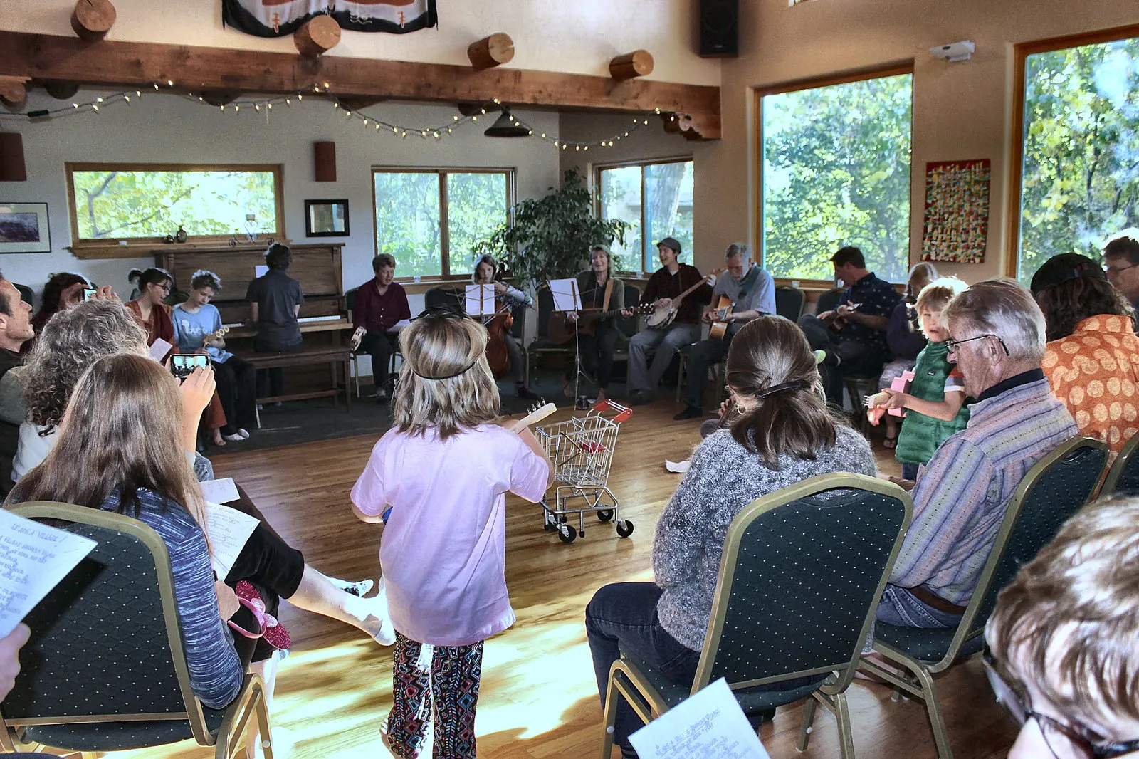 Multigenerational community gathering in the Common House with families, children, and elders seated in a circle