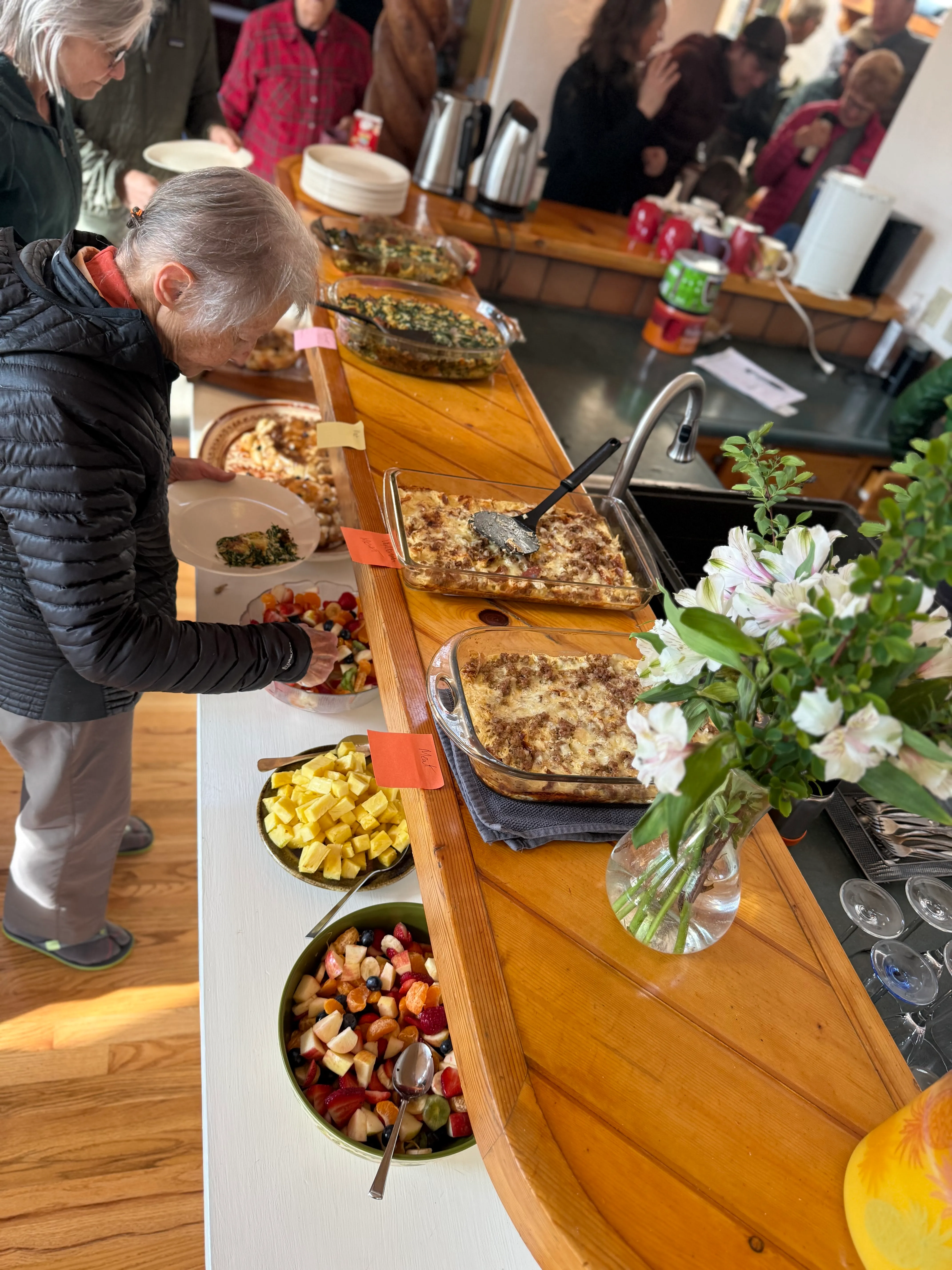 Community meal buffet spread with homemade dishes and residents gathering around