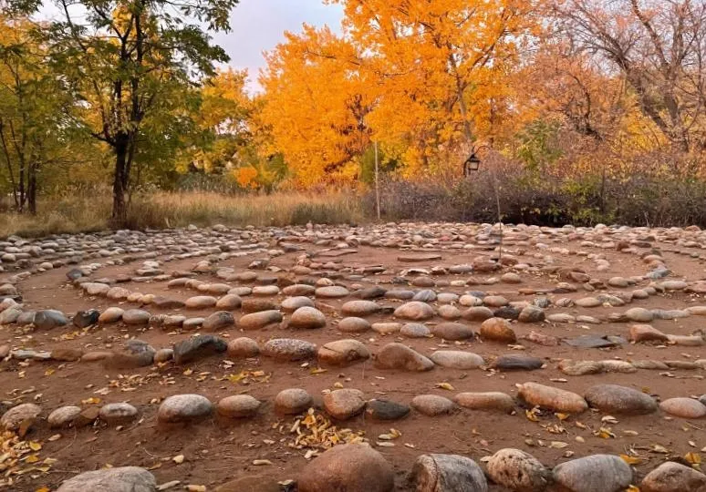 Stone labyrinth meditation space surrounded by golden autumn trees